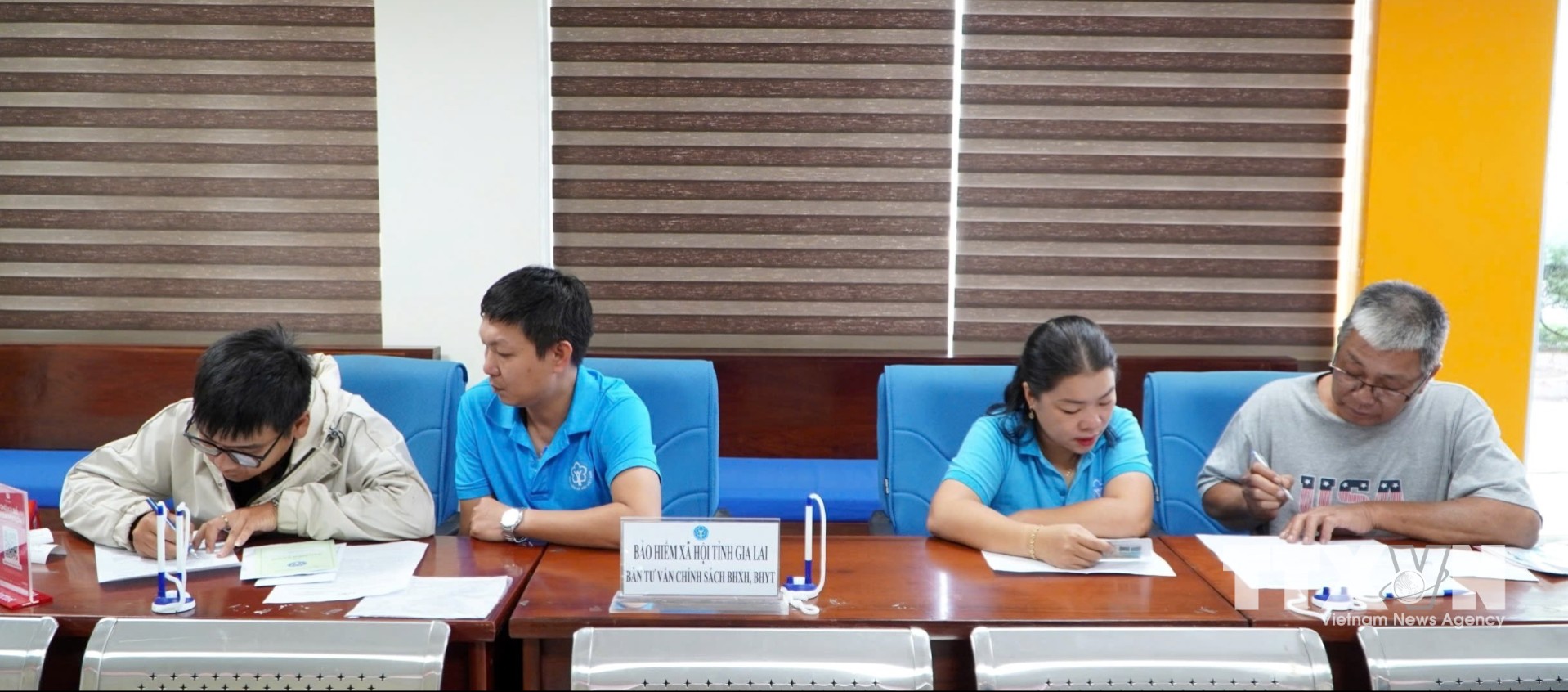 Các cán bộ, nhân viên Bảo hiểm xã hội tỉnh Gia Lai hỗ trợ, hướng dẫn người tham gia bảo hiểm sử dụng ứng dụng VssID. (Ảnh: Quang Thái/TTXVN)